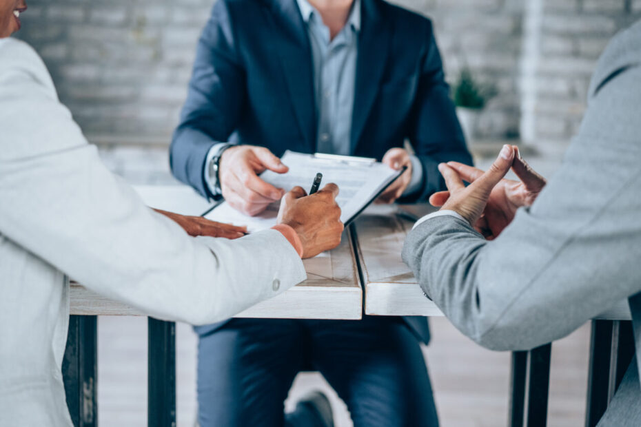 A corporate attorney in Los Angeles signs a business settlement contract during a boardroom meeting.