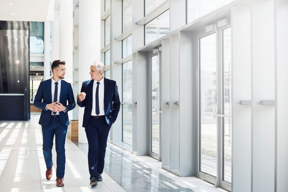 Two corporate lawyers talking calmly by an office window discussing a corporate governance dispute.